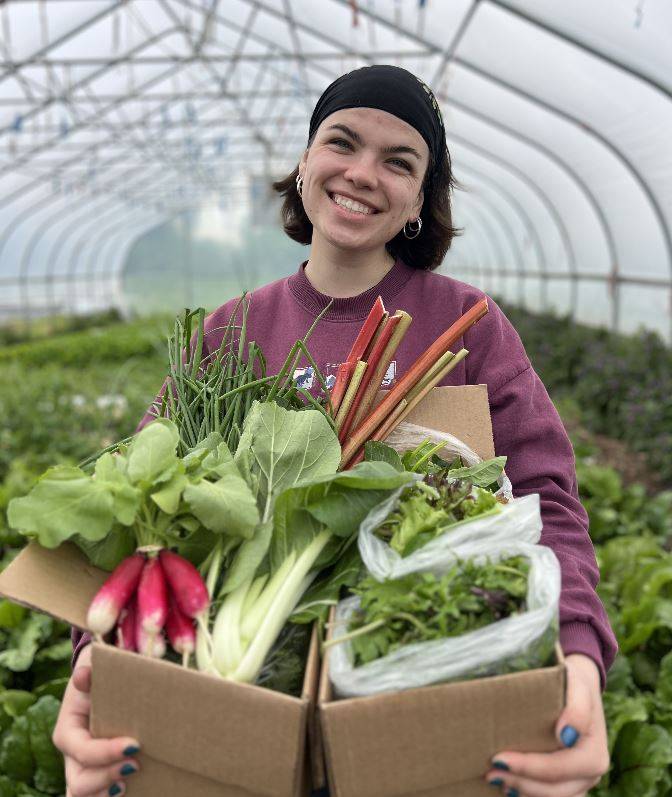 Student posing with a full CSA share.